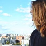 A woman standing on a rooftop, gazing over Saint Petersburg's urban skyline on a clear, sunny day.