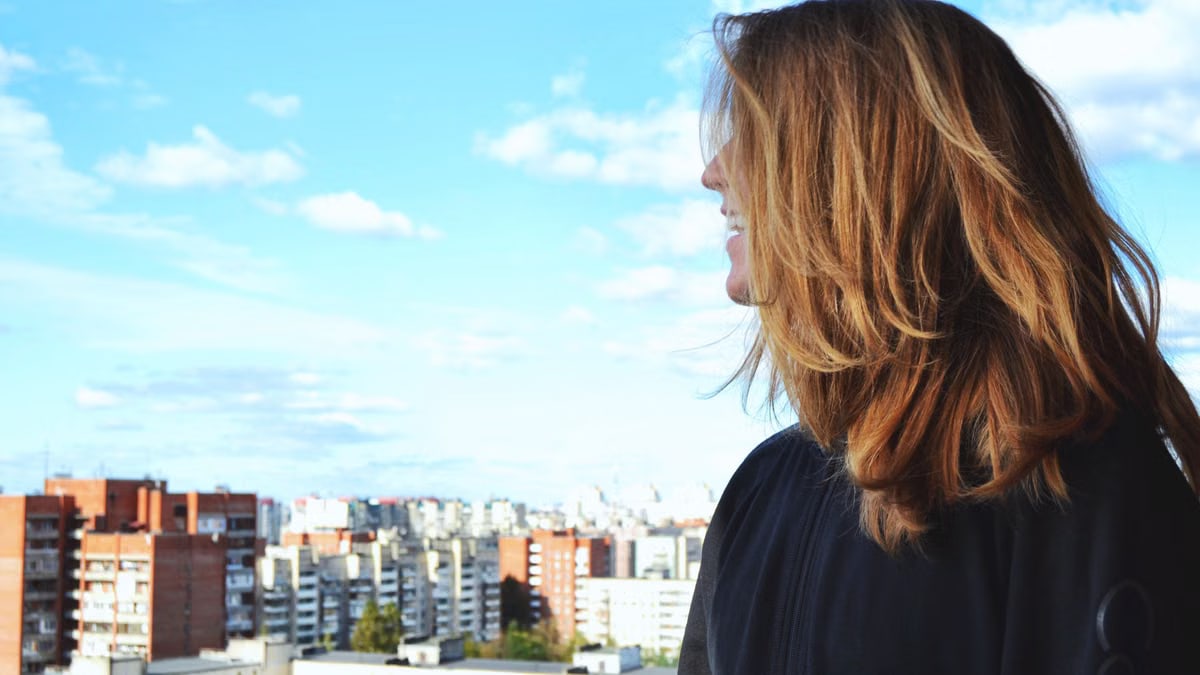 A woman standing on a rooftop, gazing over Saint Petersburg's urban skyline on a clear, sunny day.
