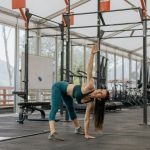 Caucasian woman stretching in a modern gym environment, promoting fitness and exercise.